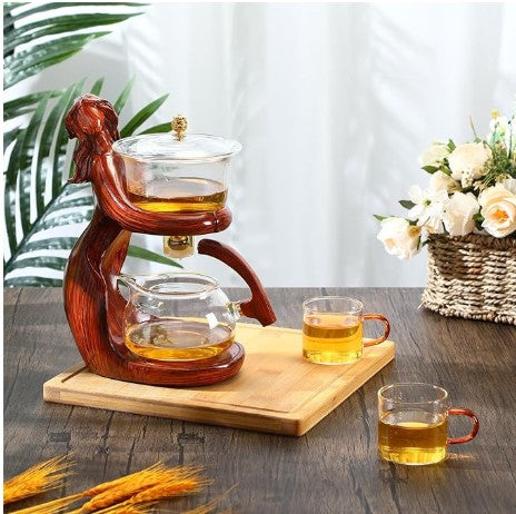 Semi-Automatic Tea set with glass teapot and cups on a wooden stand, accompanied by a basket of flowers and plants.